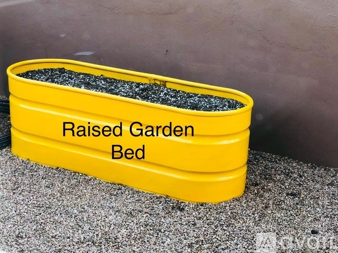 A yellow raised garden bed is filled with soil.
