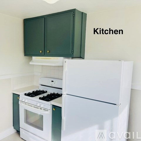 A kitchen with green cabinets and white appliances.