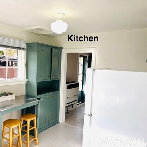 A kitchen with green cabinets and a white refrigerator.