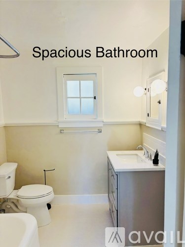 A spacious bathroom with a toilet, sink, and bathtub.