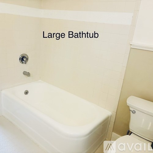 A large white bathtub is in a bathroom with a toilet.
