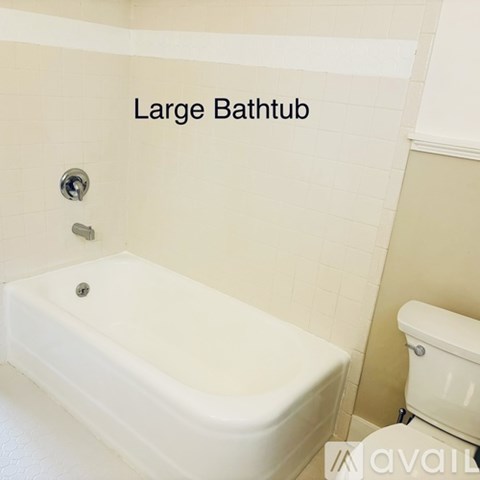 A large white bathtub is in a bathroom with a toilet.