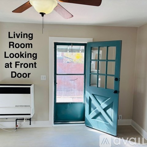 A living room with a blue door and a ceiling fan.
