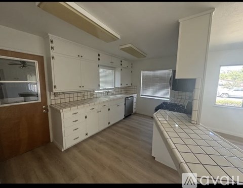 A kitchen with white cabinets and a wooden door.