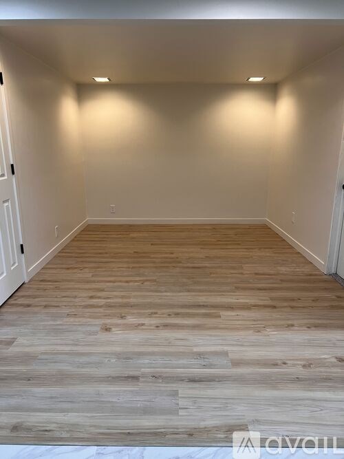 A room with wooden flooring and white walls.