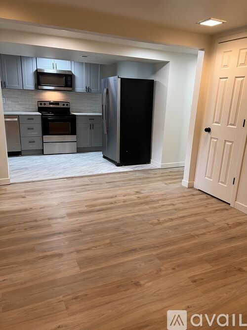 A kitchen with wooden floors and a black refrigerator.