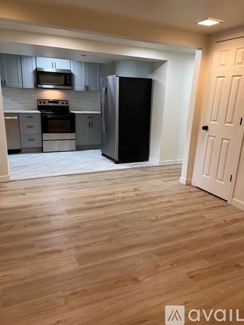 A kitchen with wooden floors and a black refrigerator.