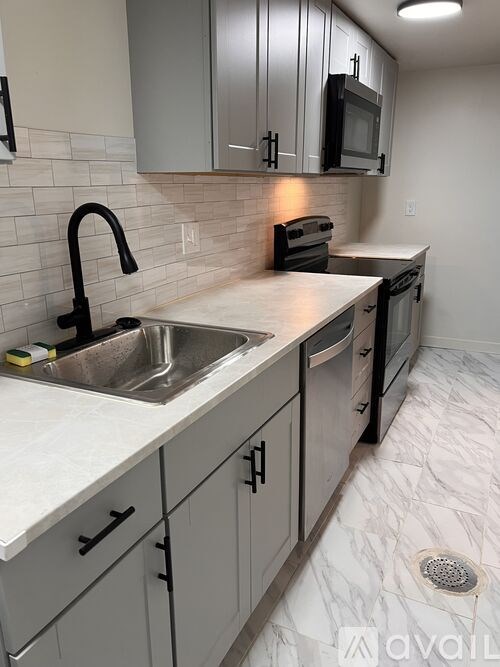A kitchen with a sink, stove, and microwave.