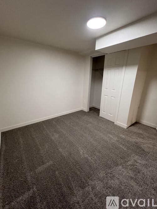 A carpeted room with a door and a light on the ceiling.