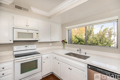 A kitchen with white cabinets and appliances.