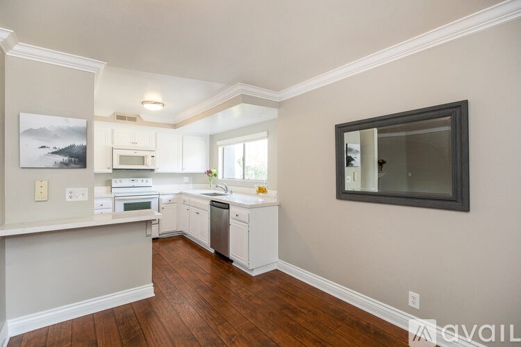 A kitchen with white cabinets and a wooden floor.