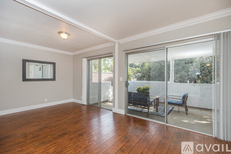 A room with wooden floors and a sliding glass door leading to a balcony.