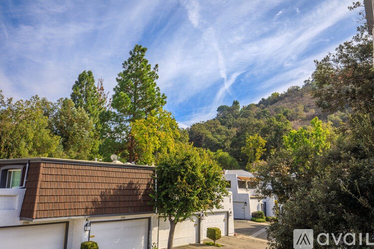 A house with a brown roof is surrounded by trees and bushes.