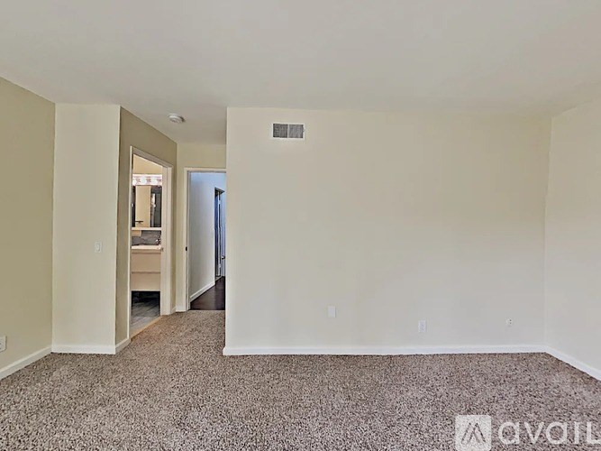 A carpeted room with a doorway leading to another room.