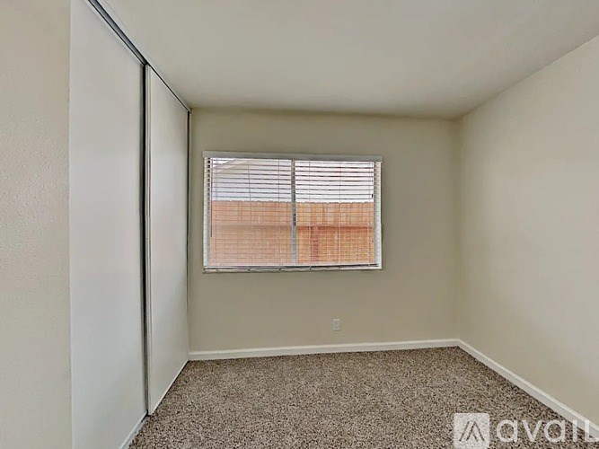 A room with a carpeted floor and a window with blinds.