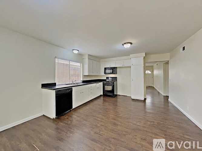 A spacious kitchen with white cabinets and a black countertop.