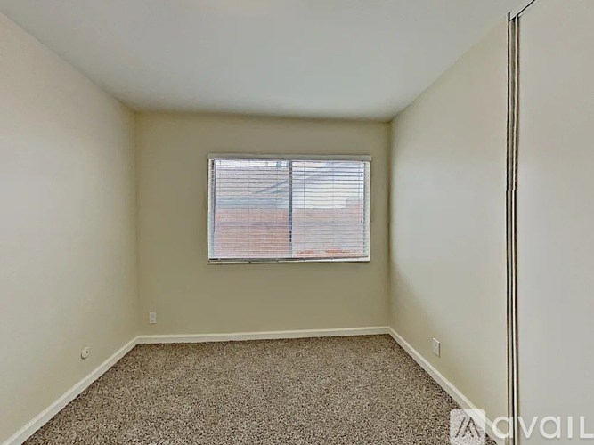 A room with a carpeted floor and a window with blinds.