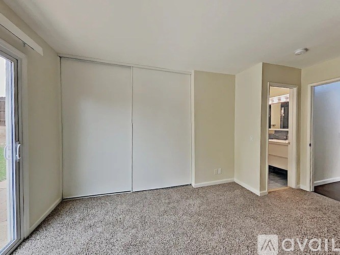 A room with white walls and carpeted floor with a door on the left.