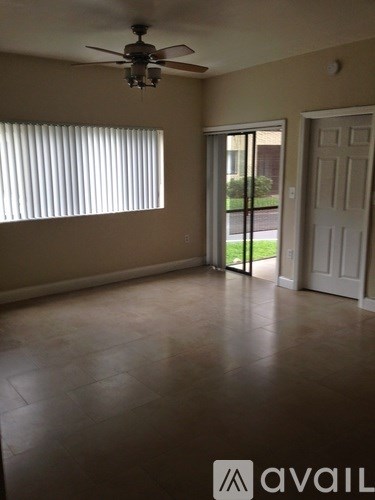 A room with a ceiling fan and sliding glass doors.