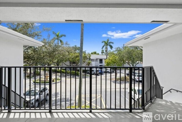 A balcony with a black railing overlooks a parking lot.