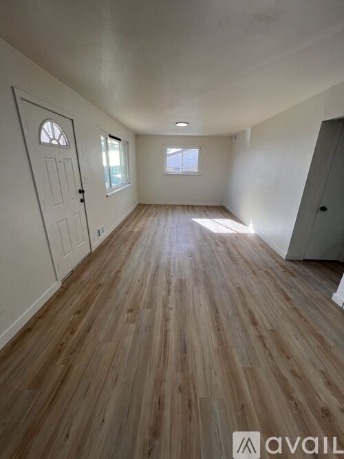 A room with wooden flooring and white walls.