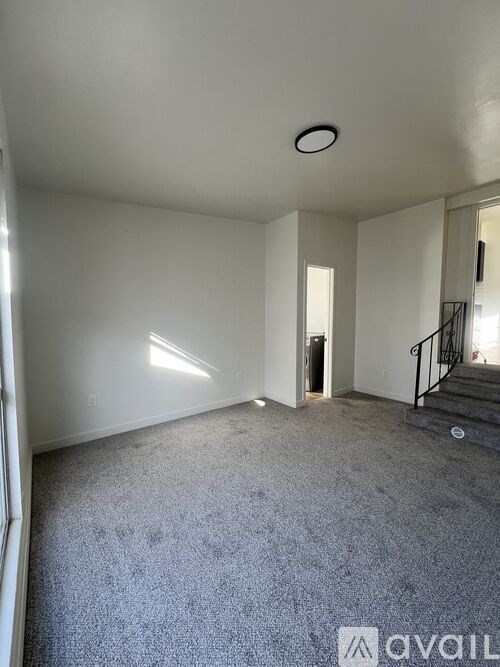 A room with a carpeted floor and a staircase.