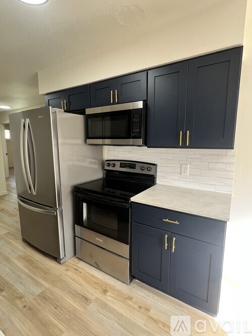 A kitchen with a refrigerator, microwave, oven, and cabinets.