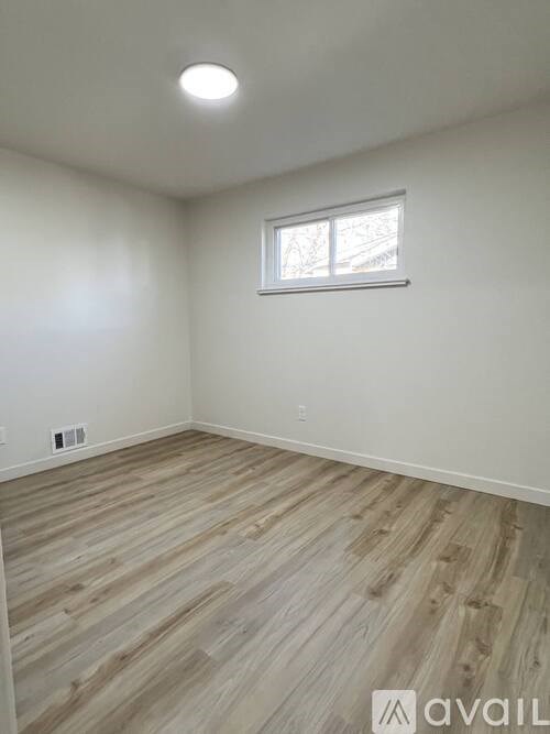 A room with wooden flooring and a window.