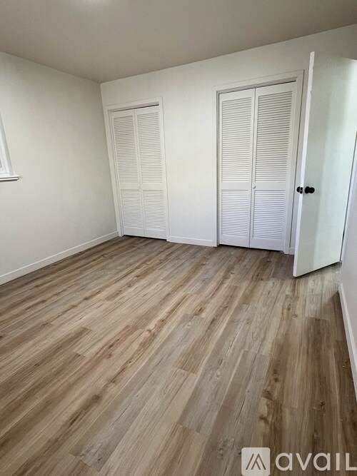 A room with wooden flooring and two white doors.