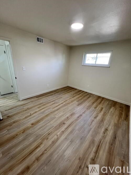 A room with wooden flooring and a window.