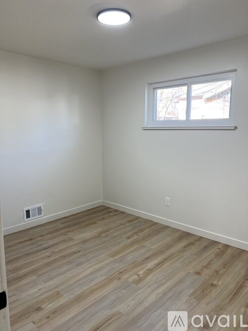 A room with a window and wooden flooring.