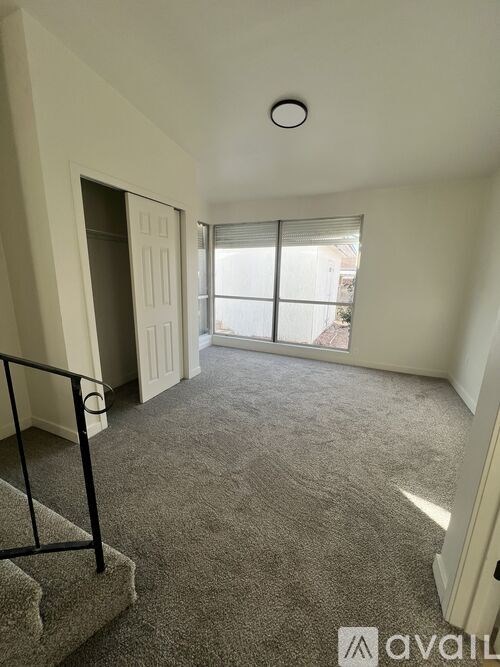 A carpeted room with a staircase leading to a door.