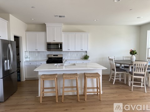 A kitchen with white cabinets and a white island with bar stools.