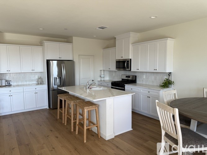A kitchen with white cabinets and a wooden floor.