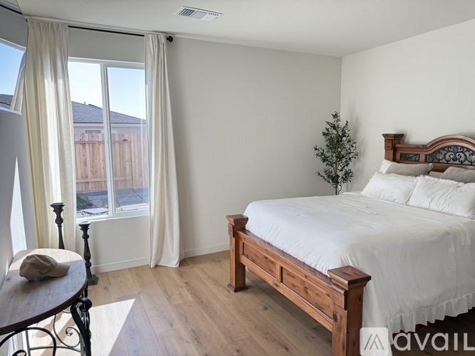 A bedroom with a bed, a chair, and a window with curtains.