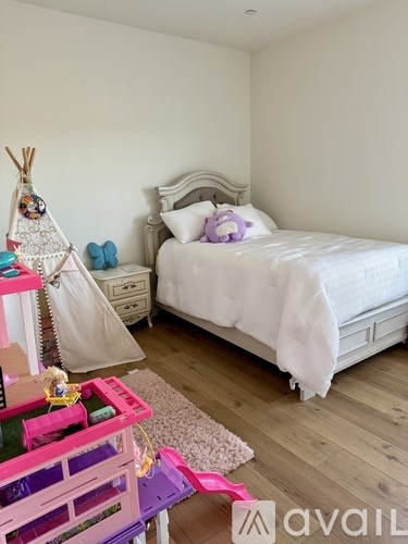 A child's bedroom with a white bed and a teepee playhouse.
