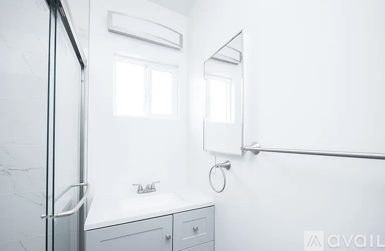 A white bathroom with a glass shower door and a marble counter.