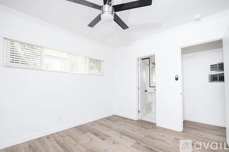 A room with a ceiling fan and wooden flooring.