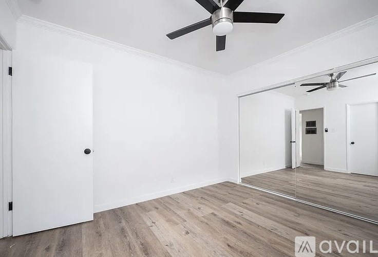 A room with a ceiling fan and wooden flooring.