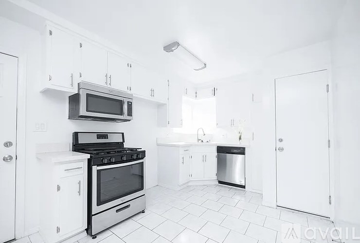 A white kitchen with a black stove and microwave.