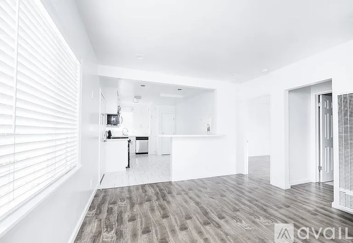A spacious, empty room with white walls and a wooden floor.