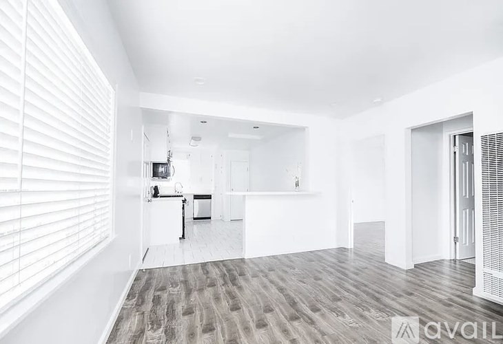 A spacious, empty room with white walls and a wooden floor.
