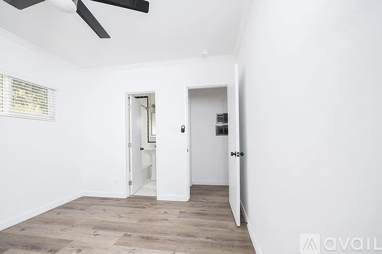 A room with a ceiling fan and two doors, one of which is open.
