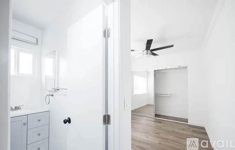 A white door is open to a room with a ceiling fan.