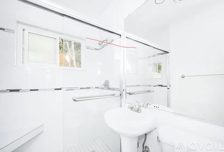 A white bathroom with a sink, mirror, and shower.