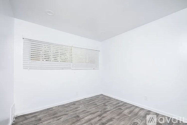 A room with wooden flooring and a window with blinds.