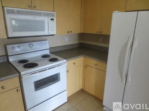 A kitchen with a white stove, microwave, and refrigerator.