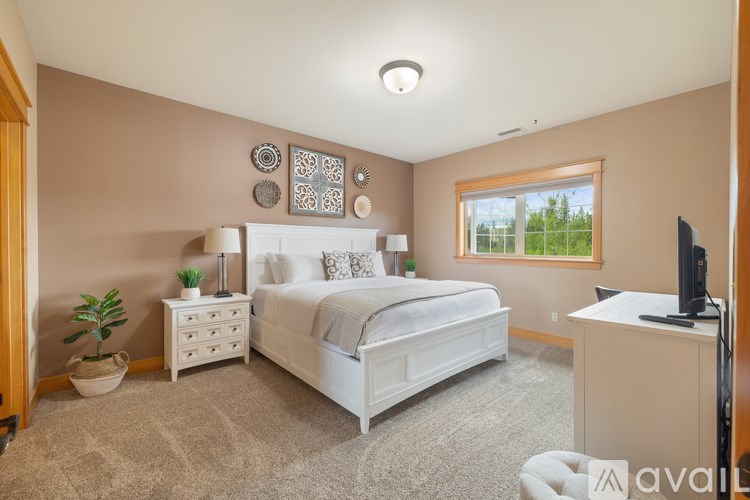 A bedroom with a large bed, a nightstand, a dresser, and a television.