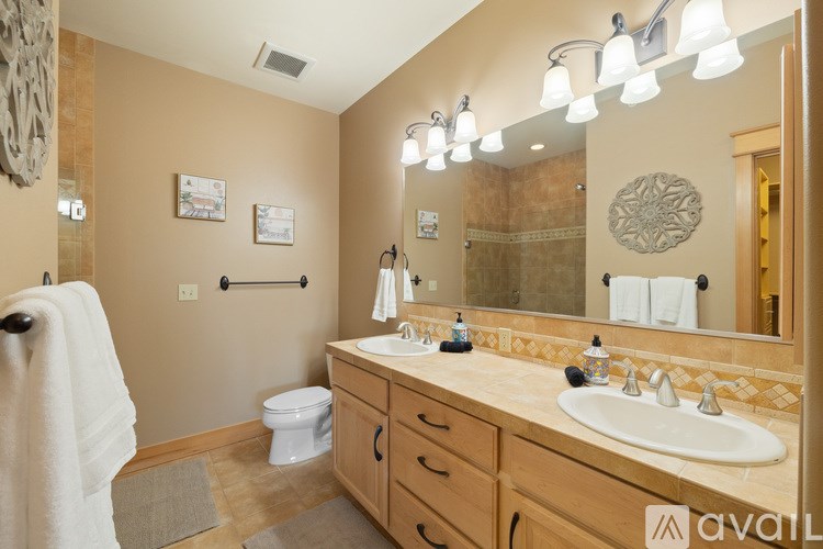 A bathroom with a toilet, sink, mirror, and towel rack.