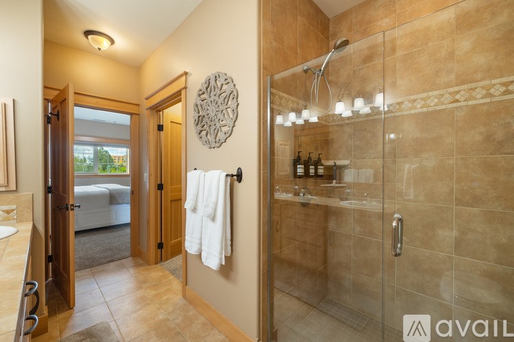 A bathroom with a glass shower stall and a towel hanging on the door.